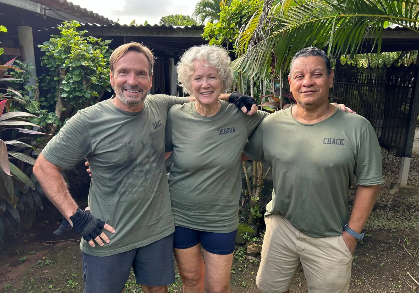 Three people smiling in matching green shirts.